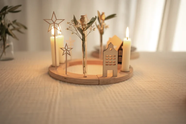 Länglicher Adventskranz für Stabkerzen mit weißen Kerzen, Holzsternen und schlichten Häuschen aus Holz.